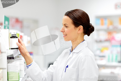 Image of happy female apothecary with drug at pharmacy