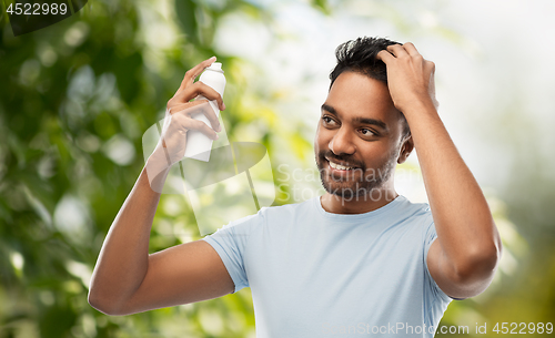 Image of man applying hair spray over natural background