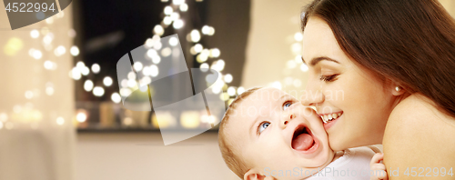Image of close up of mother with baby over christmas lights