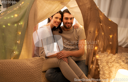 Image of happy couple in kids tent at home