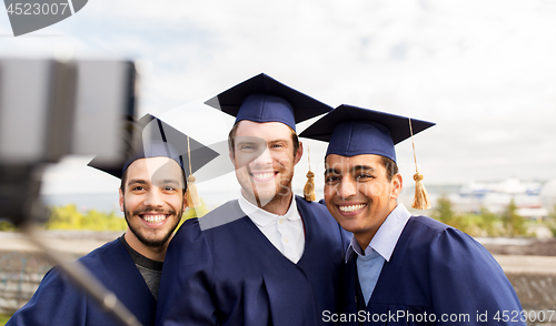 Image of happy male students taking picture by selfie stick