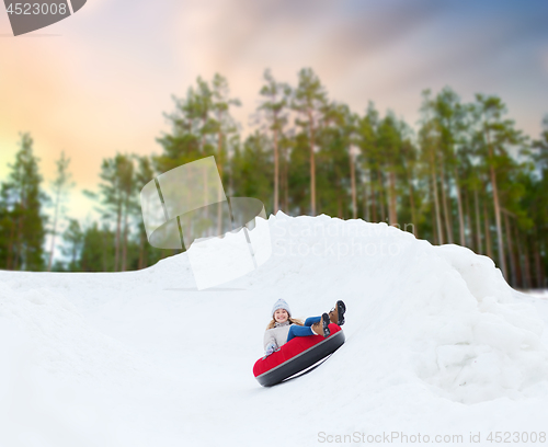 Image of happy teenage girl sliding down hill on snow tube