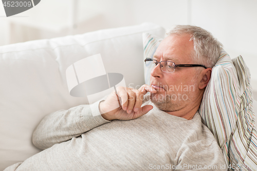 Image of senior man  lying on sofa and thinking at home