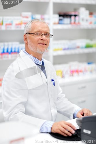 Image of senior apothecary at pharmacy cash register