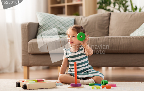 Image of happy baby girl playing with toy blocks at home