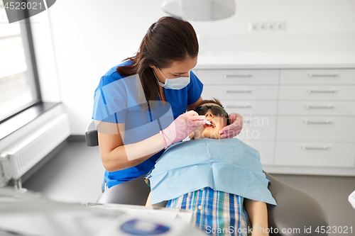 Image of dentist checking for kid teeth at dental clinic