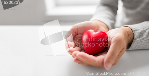 Image of cupped senior man hands with red heart shape