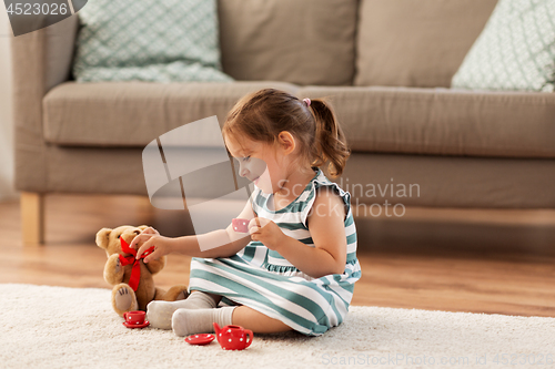 Image of little girl playing with toy tea set at home