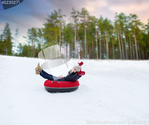 Image of happy teenage girl sliding down hill on snow tube