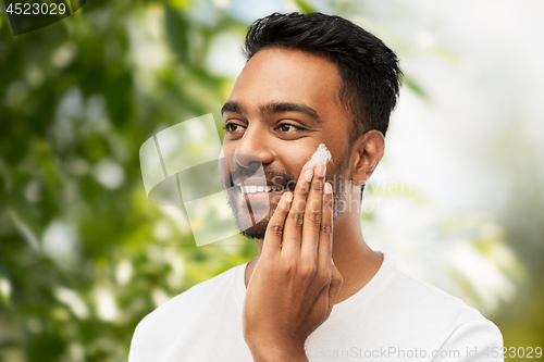 Image of man applying cream to face over natural background