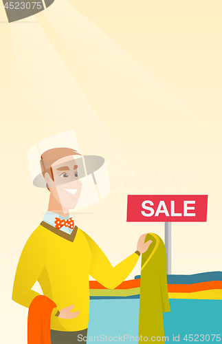 Image of Young man choosing clothes in the shop on sale.