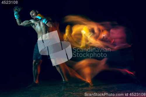 Image of Male boxer boxing in a dark studio