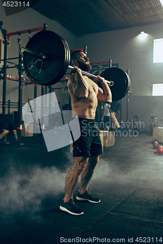 Image of Fit young man lifting barbells working out in a gym