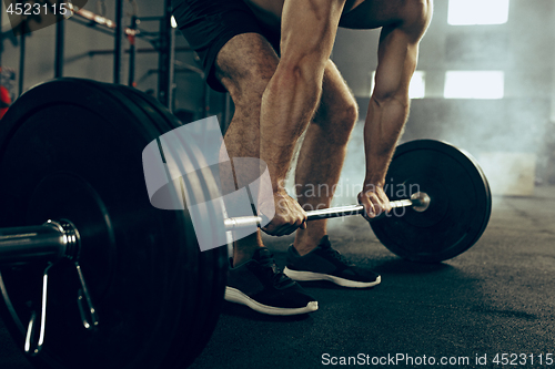 Image of Fit young man lifting barbells working out in a gym