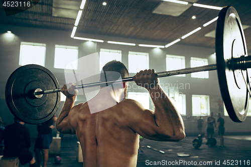 Image of Fit young man lifting barbells working out in a gym