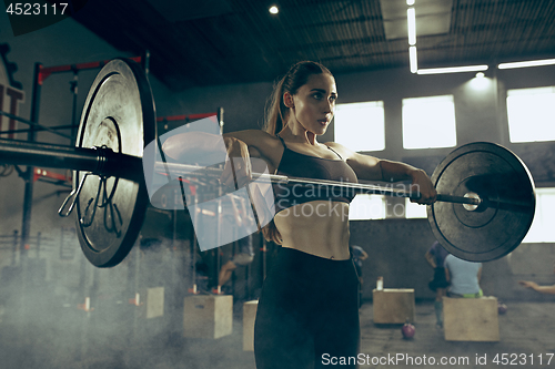 Image of Fit young woman lifting barbells working out in a gym