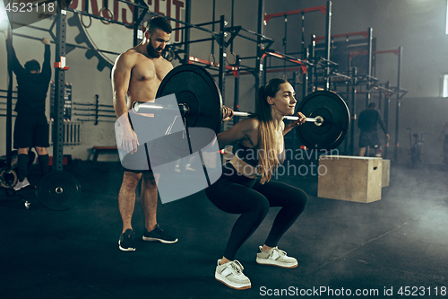 Image of Fit young woman lifting barbells working out in a gym