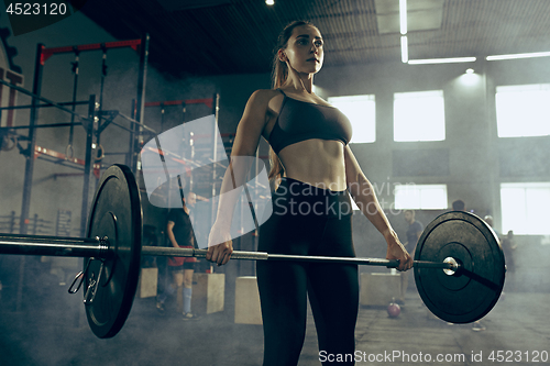 Image of Fit young woman lifting barbells working out in a gym