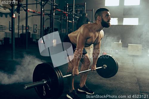 Image of Fit young man lifting barbells working out in a gym