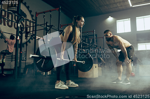 Image of Fit young woman lifting barbells working out in a gym