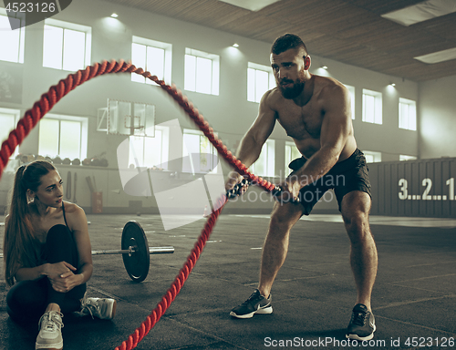 Image of Men with battle rope battle ropes exercise in the fitness gym.