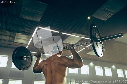 Image of Fit young man lifting barbells working out in a gym