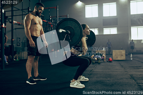 Image of Fit young woman lifting barbells working out in a gym