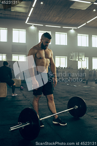 Image of Fit young man lifting barbells working out in a gym