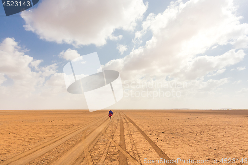 Image of Solitary masai worrior walking along salt lake desert road in Kenya, Amboseli Natural Park, Africa