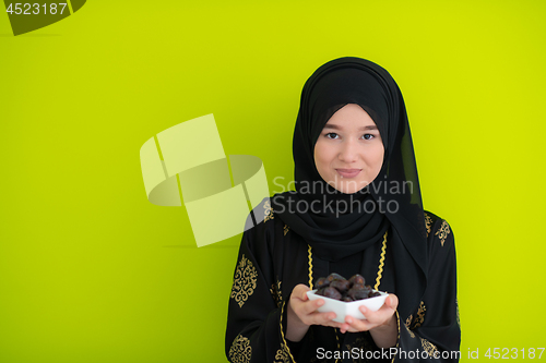 Image of modern muslim woman holding a plate of dates in ramadan kareem o