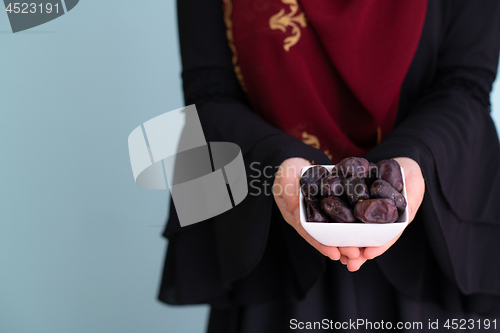 Image of modern muslim woman holding a plate of dates in ramadan kareem