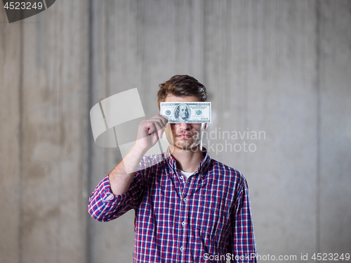 Image of business man holding american dollars banknote over the eyes