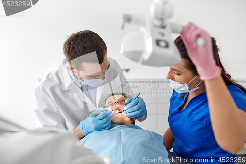 Image of dentist checking for kid teeth at dental clinic