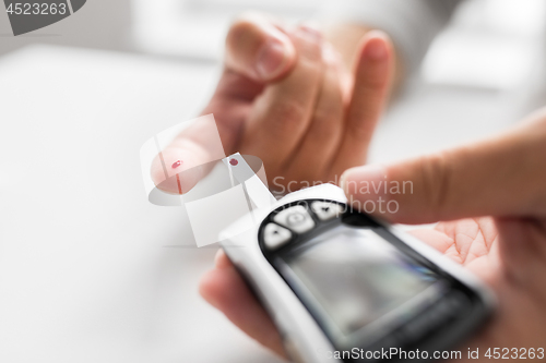 Image of senior man with glucometer checking blood sugar