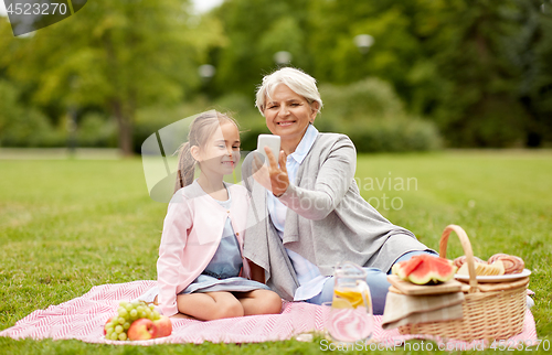 Image of grandmother and granddaughter take selfie at park