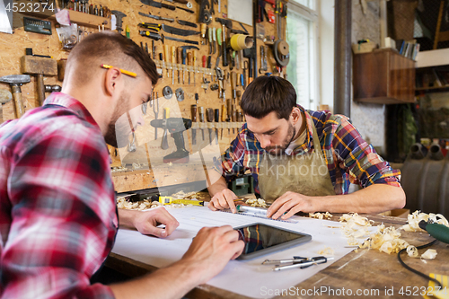 Image of carpenters with tablet and blueprint at workshop