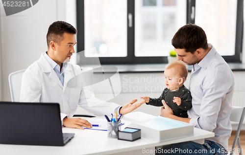 Image of father with baby and doctor at clinic