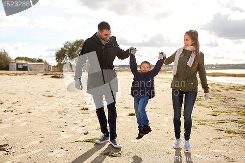 Image of happy family walking along autumn beach