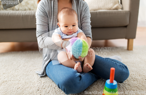 Image of mother and baby son playing with ball at home