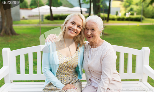 Image of daughter with senior mother hugging on park bench