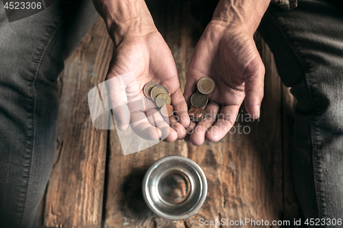 Image of Male beggar hands seeking money on the wooden floor at public path way