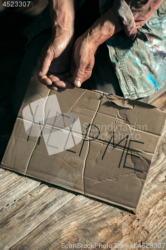 Image of Male beggar hands seeking money on the wooden floor at public path way