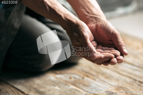 Image of Male beggar hands seeking money on the wooden floor at public path way