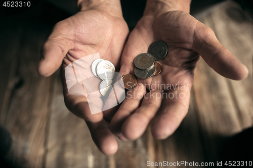 Image of Male beggar hands seeking money on the wooden floor at public path way