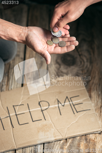 Image of Male beggar hands seeking money on the wooden floor at public path way