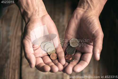 Image of Male beggar hands seeking money on the wooden floor at public path way