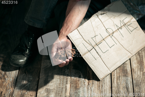 Image of Male beggar hands seeking money on the wooden floor at public path way