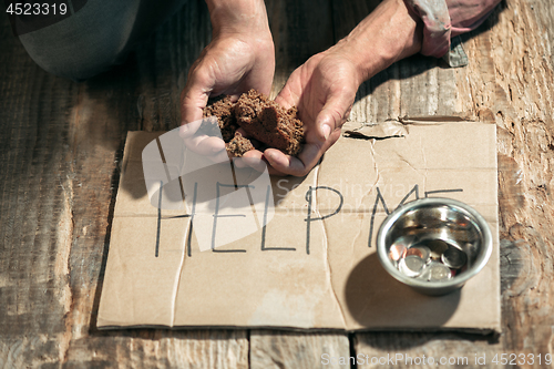 Image of Male beggar hands seeking money on the wooden floor at public path way