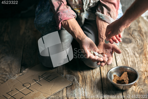 Image of Male beggar hands seeking money on the wooden floor at public path way