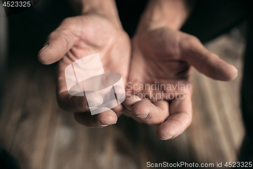 Image of Male beggar hands seeking money on the wooden floor at public path way